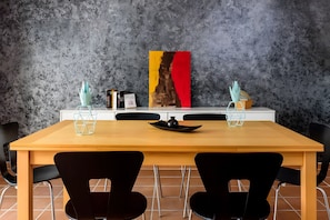 Une table à manger avec deux chaises, un tableau et un vase posé sur la table.