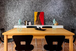A dining table with chairs, a painting, and decorative items on the table.
