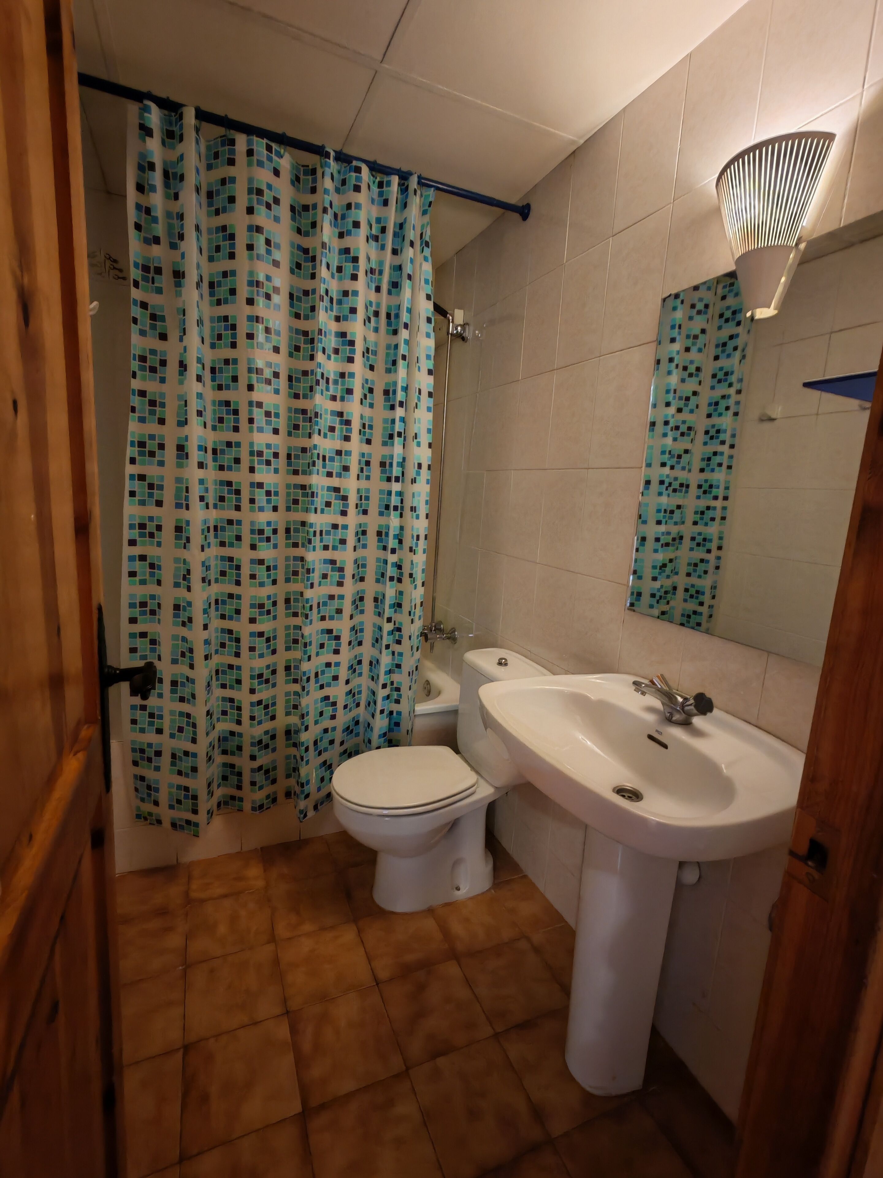 Un baño con inodoro, lavamanos y cortina de ducha.