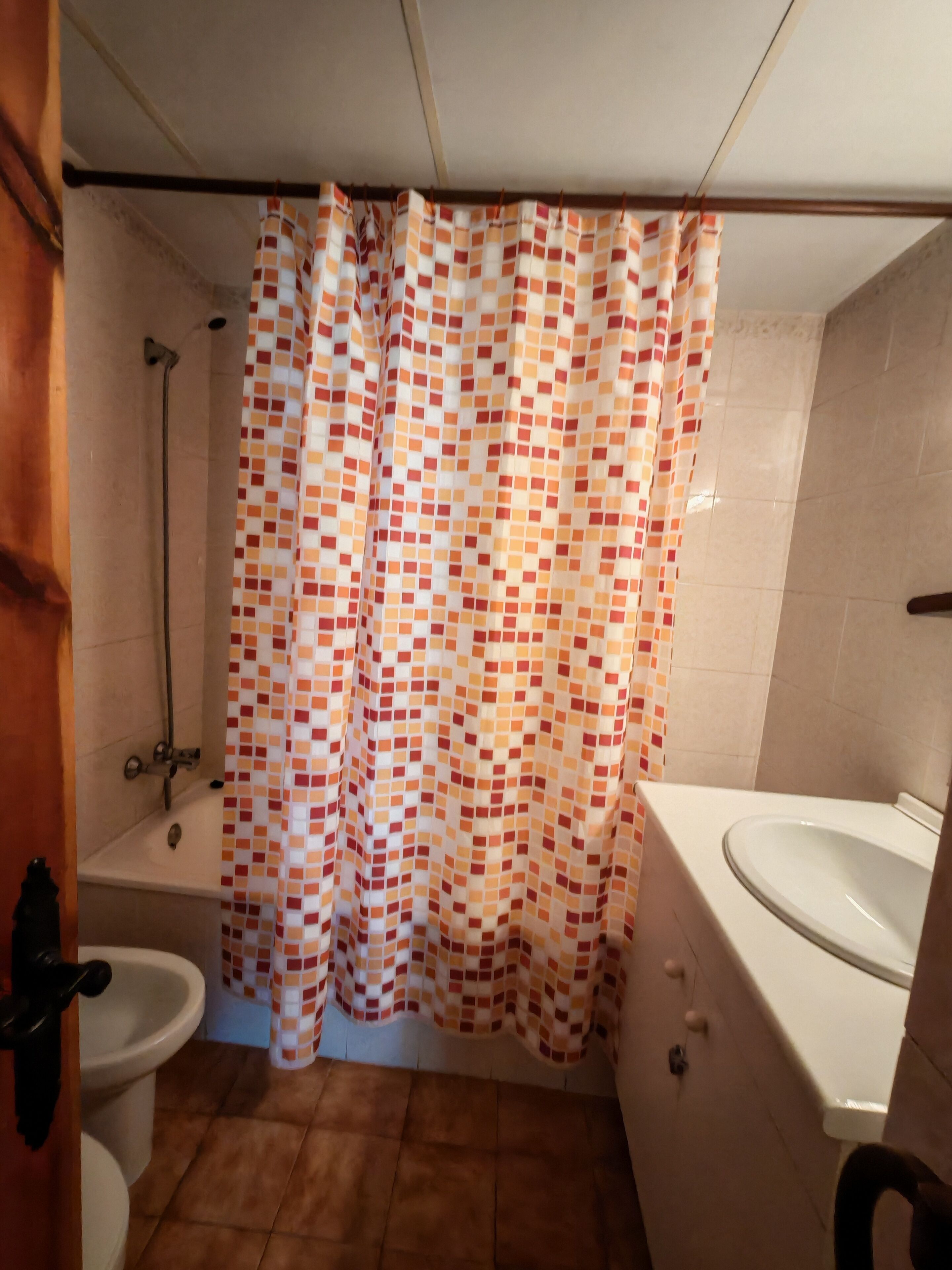 Ein Badezimmer mit gefliestem Boden, einer Dusche, einer Toilette und einem Waschbecken.