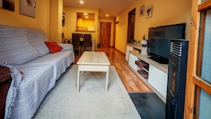 Una sala de estar con sofá, mesa de centro, televisor y zona de cocina.