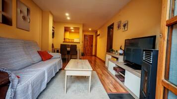 A living room with a sofa, coffee table, TV, and kitchen area.