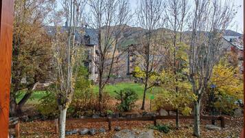 A view of a building with a stone facade, surrounded by trees and a grassy area.