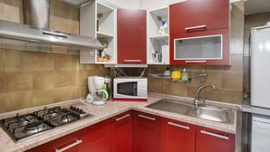 A kitchen with red cabinets, a gas stove, a microwave, and a sink. - Apartment 'Alassio Mare E Non Solo' with Sea View, Wi-Fi and Air Conditioning (Alassio)