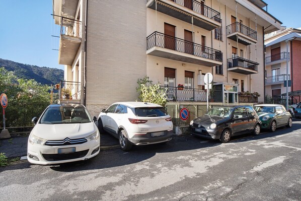 A row of parked cars in front of a multi-story building with balconies.