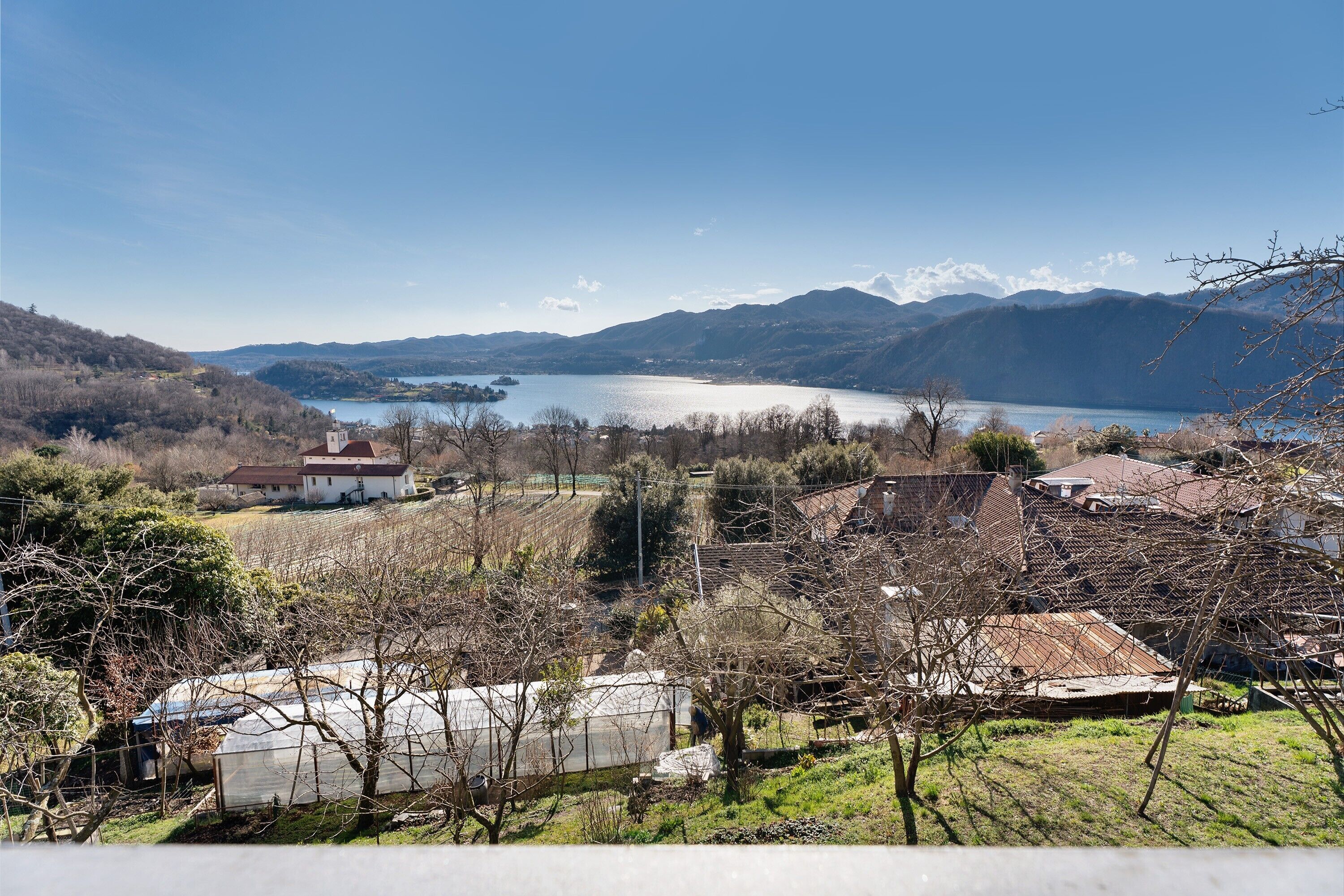 Paisaje rural con un lago, montañas y casas.