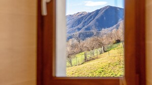 Une vue à travers une fenêtre sur un paysage montagneux, avec une clôture et un cadre de porte.