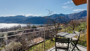 Un balcon avec une table et des chaises, donnant sur un lac et des montagnes.