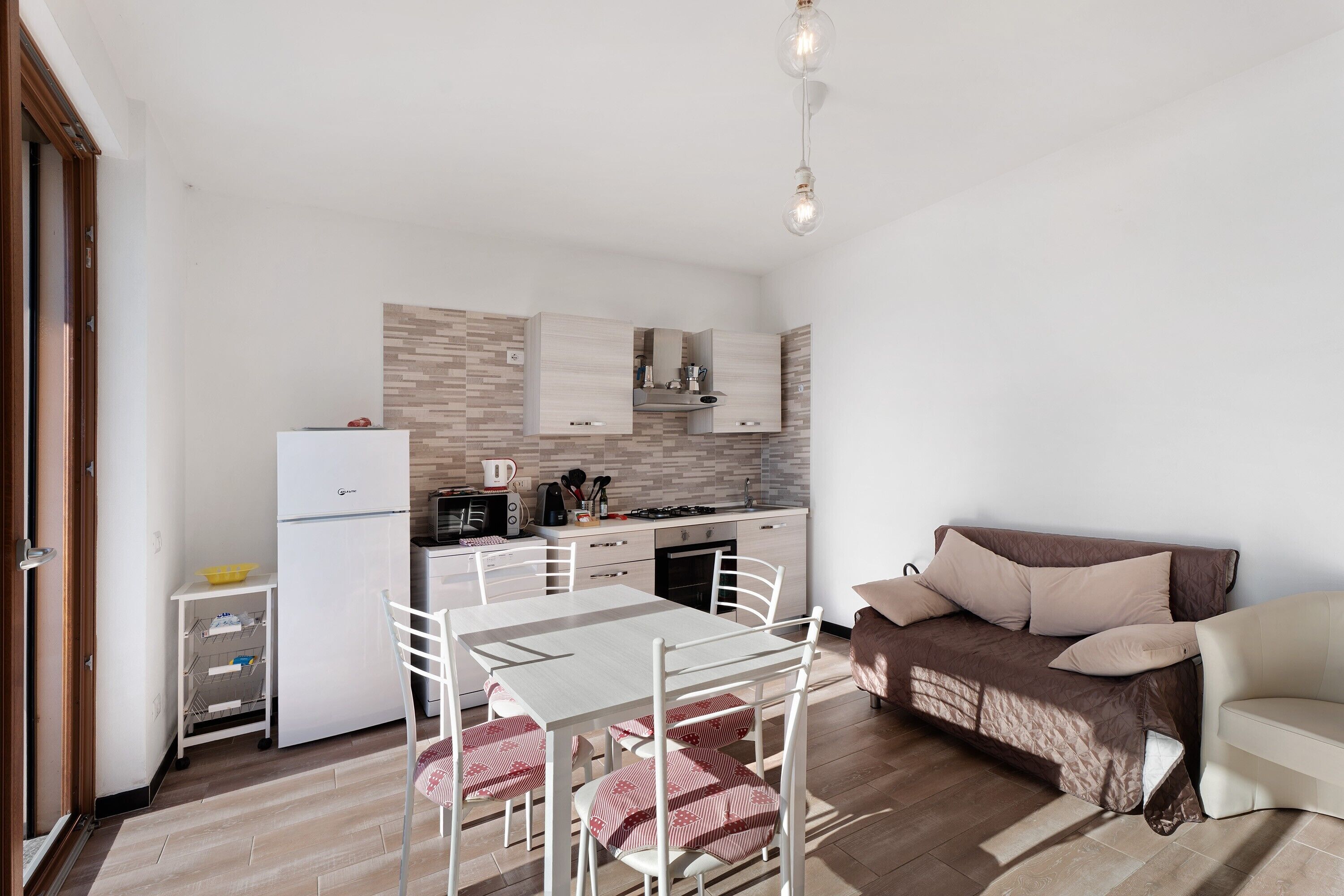 A compact living space with a kitchenette, dining area, and a sofa.