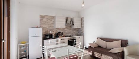 A compact living space with a kitchenette, dining area, and a sofa.