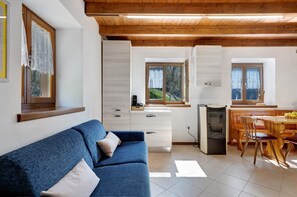 Cozinha moderna com área de refeições, teto de madeira e sofá azul.
