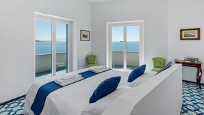 Una habitación de hotel con una cama, dos sillas, una mesita y vistas al mar.