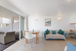 A modern living room with a dining area, a sofa, and a desk. - Apartment 'Golden Sea' with Shared Pool, Wi-Fi and Air Conditioning (Cabanas de Tavira)