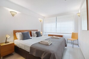 A bedroom with a bed, bedside tables, a chair, and a large window.