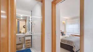A hotel room with a bed, a bathroom with a mirror, and a sink.