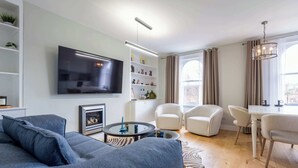 Un salon moderne doté d’un téléviseur à écran plat, d’une cheminée, d’une table basse et d’un coin repas avec des chaises.