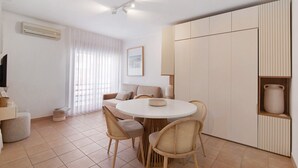 Ein moderner Essbereich mit einem runden Tisch, vier Stühlen, einer Couch und einem eingebauten Schrank mit einer Vase.