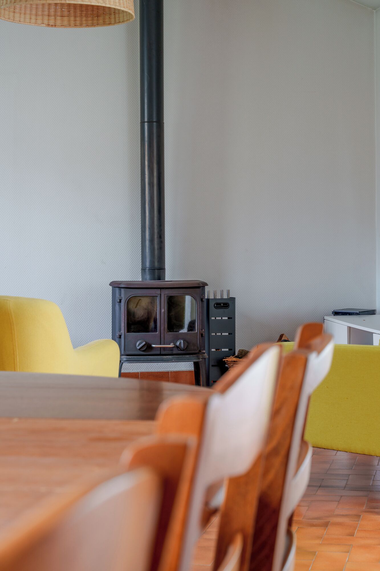 A dining area with a wooden table and chairs, a stove, and yellow chairs.