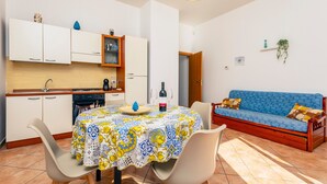 A compact living space with a dining area, kitchenette, and a blue sofa.