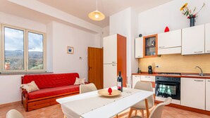 A modern kitchen with white cabinets, a dining table, and a red sofa.