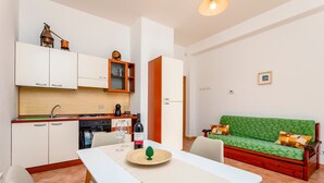 Un espacio habitable compacto con kitchenette, comedor y sofá verde.
