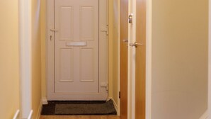 A wooden-floored hallway with a white door and a small window above it.