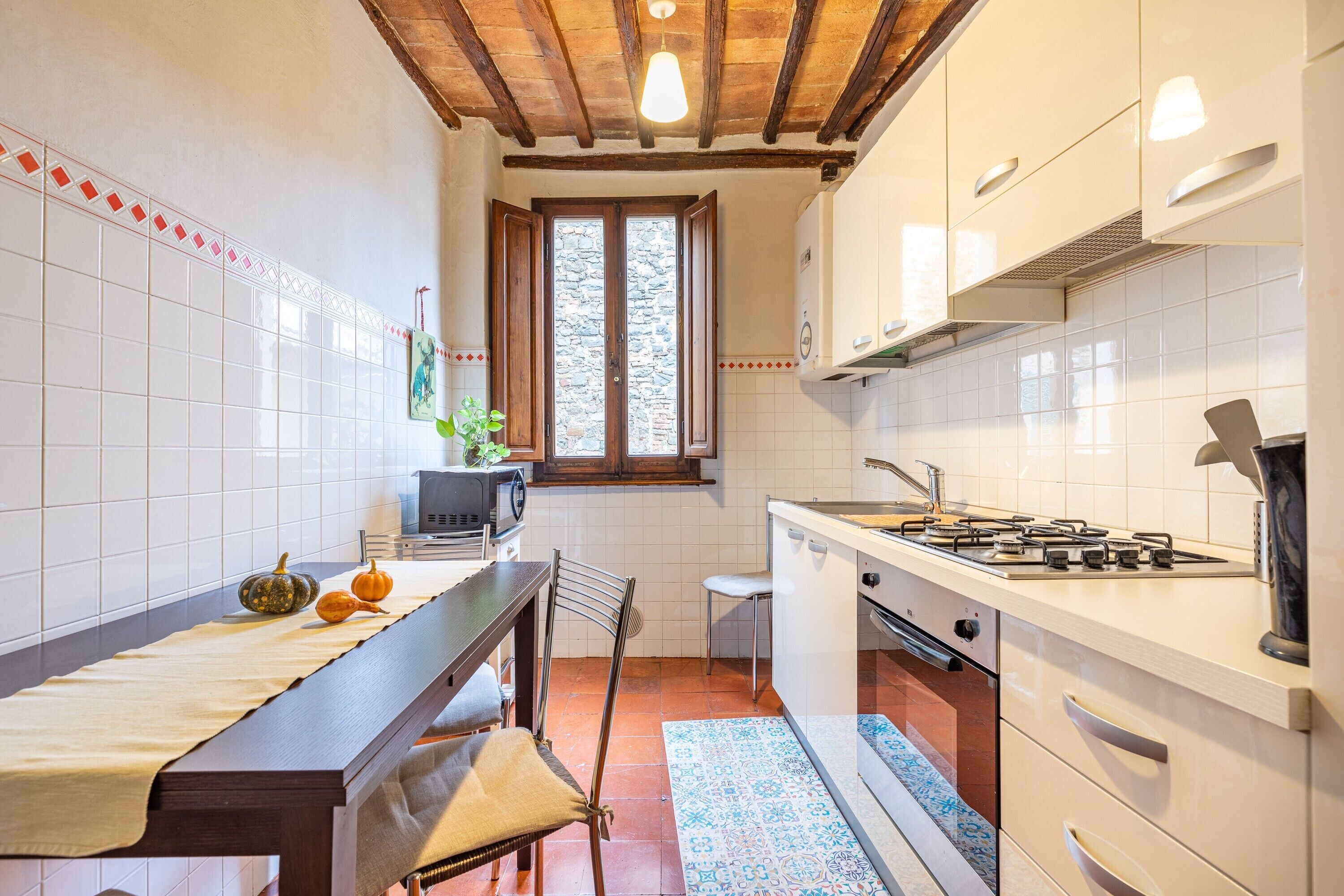 A kitchen with a wooden table, a stove, and a window.