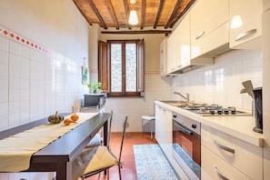 Une cuisine avec une table en bois, un poêle et une fenêtre.