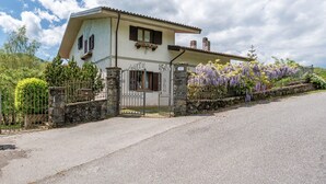 Una casa de dos pisos con un portón de piedra, un balcón pequeño y una entrada para coches.