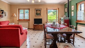 Una sala de estar con un sofá rojo, una mesa de comedor de madera y una televisión.
