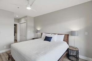 Une chambre à coucher avec un grand lit, des lampes de chevet, une petite table ronde et un ventilateur de plafond.