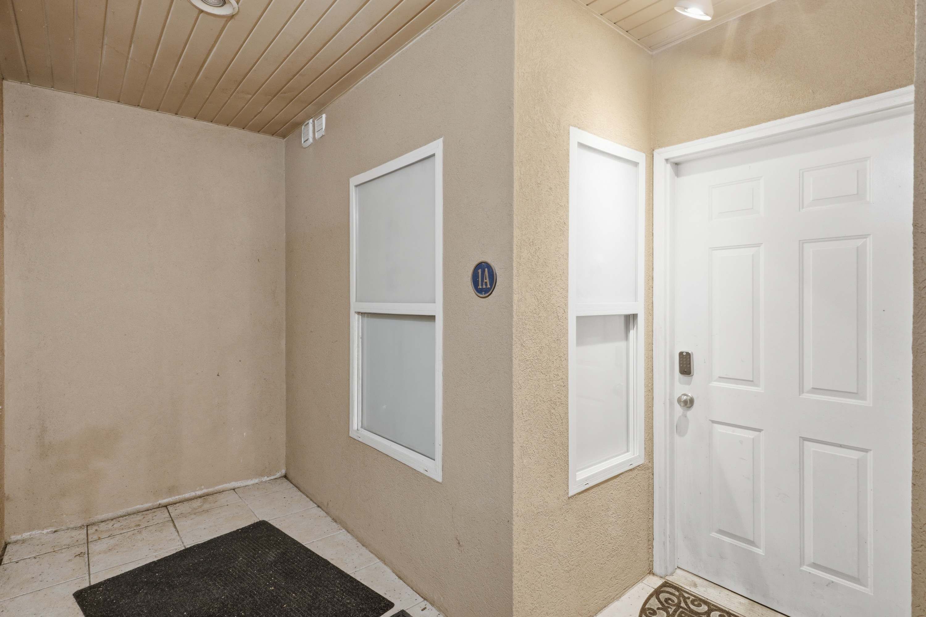 A hallway with a door, a window, and a doormat.