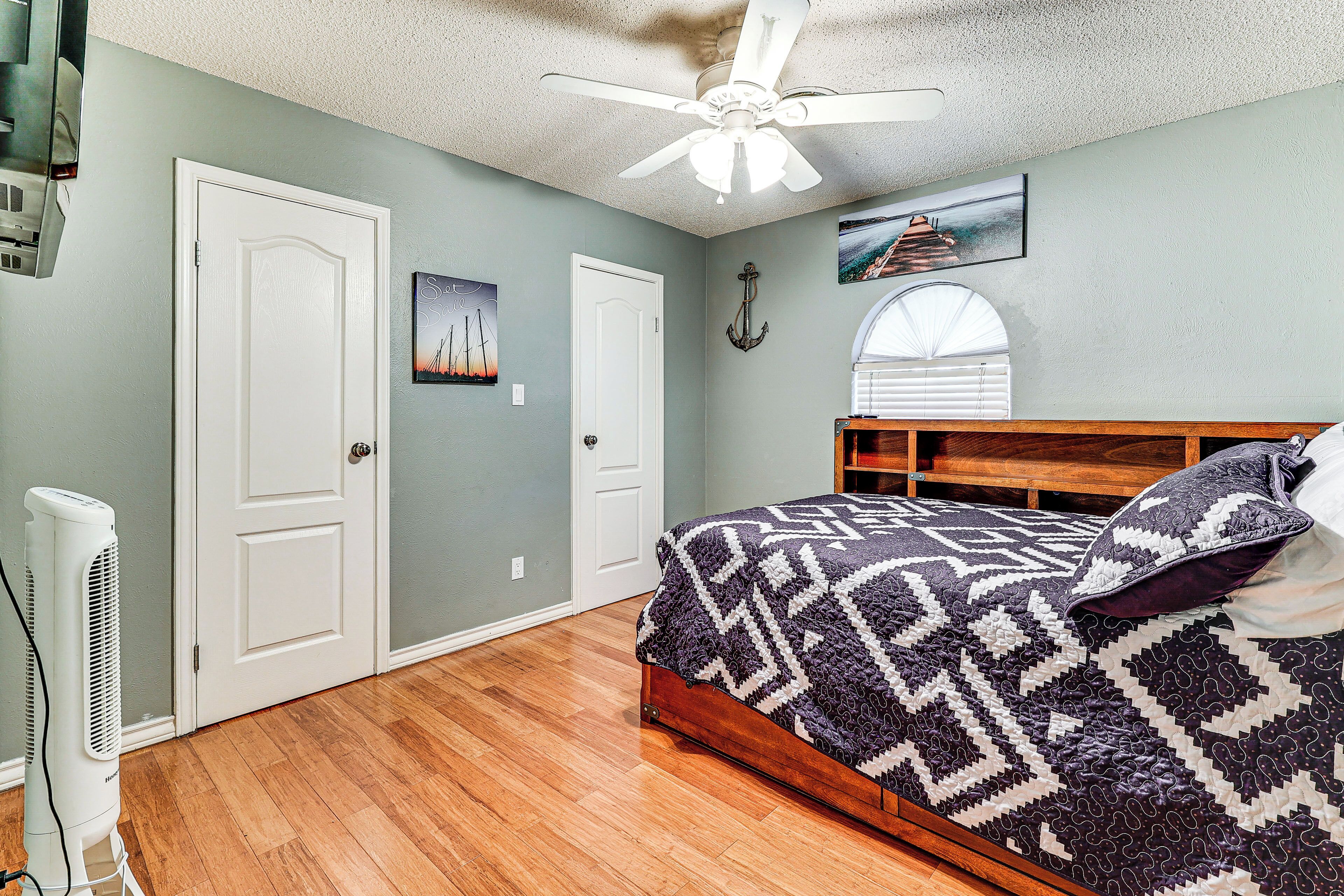 Un dormitorio con cama, ventilador de techo, ventana y puerta.