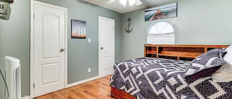 A bedroom with a bed, a ceiling fan, a window, and a door.