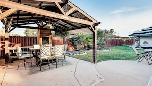 A covered patio with a wooden table and chairs, a concrete floor, and a fenced backyard. - 3 Mi to Downtown Mcallen: Quiet Home w/ Pool (McAllen)