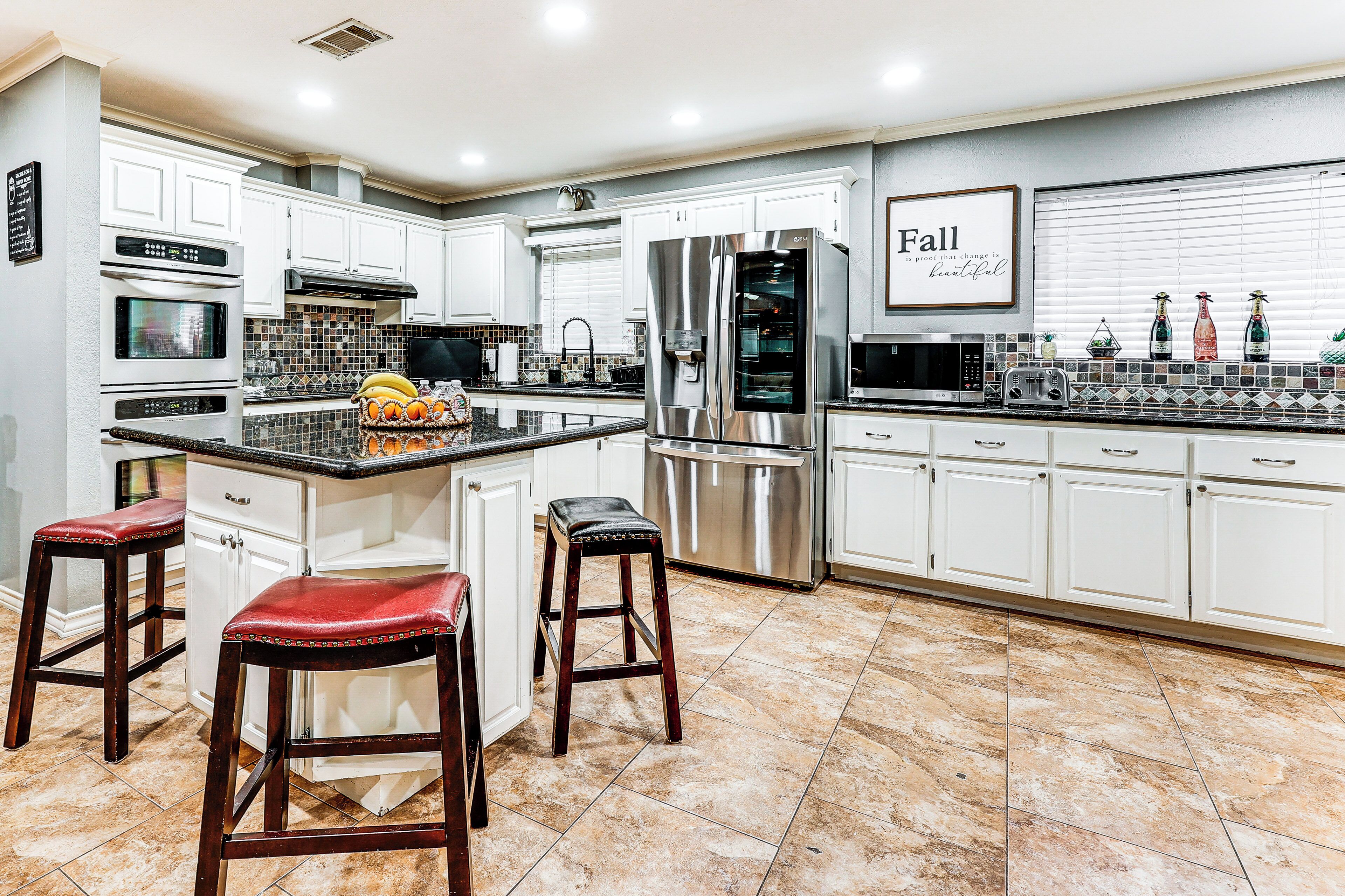 A modern kitchen with white cabinets, stainless steel appliances, and a tiled backsplash.