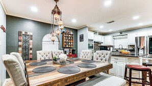 A modern kitchen with white cabinets, a stainless steel refrigerator, and a dining area with a wooden table and chairs. - 3 Mi to Downtown Mcallen: Quiet Home w/ Pool (McAllen)