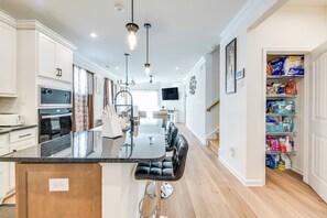A modern kitchen with a central island, built-in appliances, and a dining area with chairs.