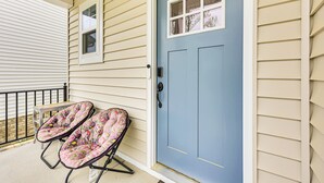 A house with a blue front door, beige siding, and two outdoor chairs with floral cushions. - 12 Mi to Dtwn Richmond: Spacious Home w/ Deck! (Richmond)