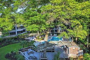 Un complexe hôtelier doté d’une piscine, d’une terrasse en bois et d’une végétation luxuriante.