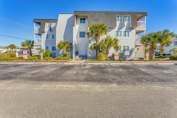 A multi-story residential building with a parking lot in front. - Walk to Ocean: North Myrtle Beach Condo w/ Pool (North Myrtle Beach)