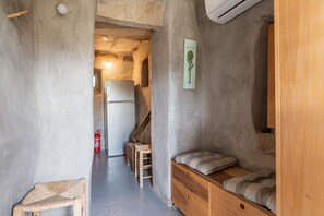 Un couloir étroit avec un banc en bois, une petite table et un escalier menant à une autre pièce.