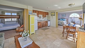 A spacious living area with a sofa, dining table, and kitchen area including cabinets and appliances. - Ocean-view Cape Cod Condo in Truro! (North Truro)