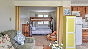 A cozy room with a bunk bed, a sofa, a wooden cabinet, and a kitchenette. - Ocean-view Cape Cod Condo in Truro! (North Truro)