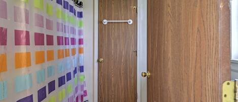Une pièce avec une porte en bois, un rideau coloré et un sol carrelé.