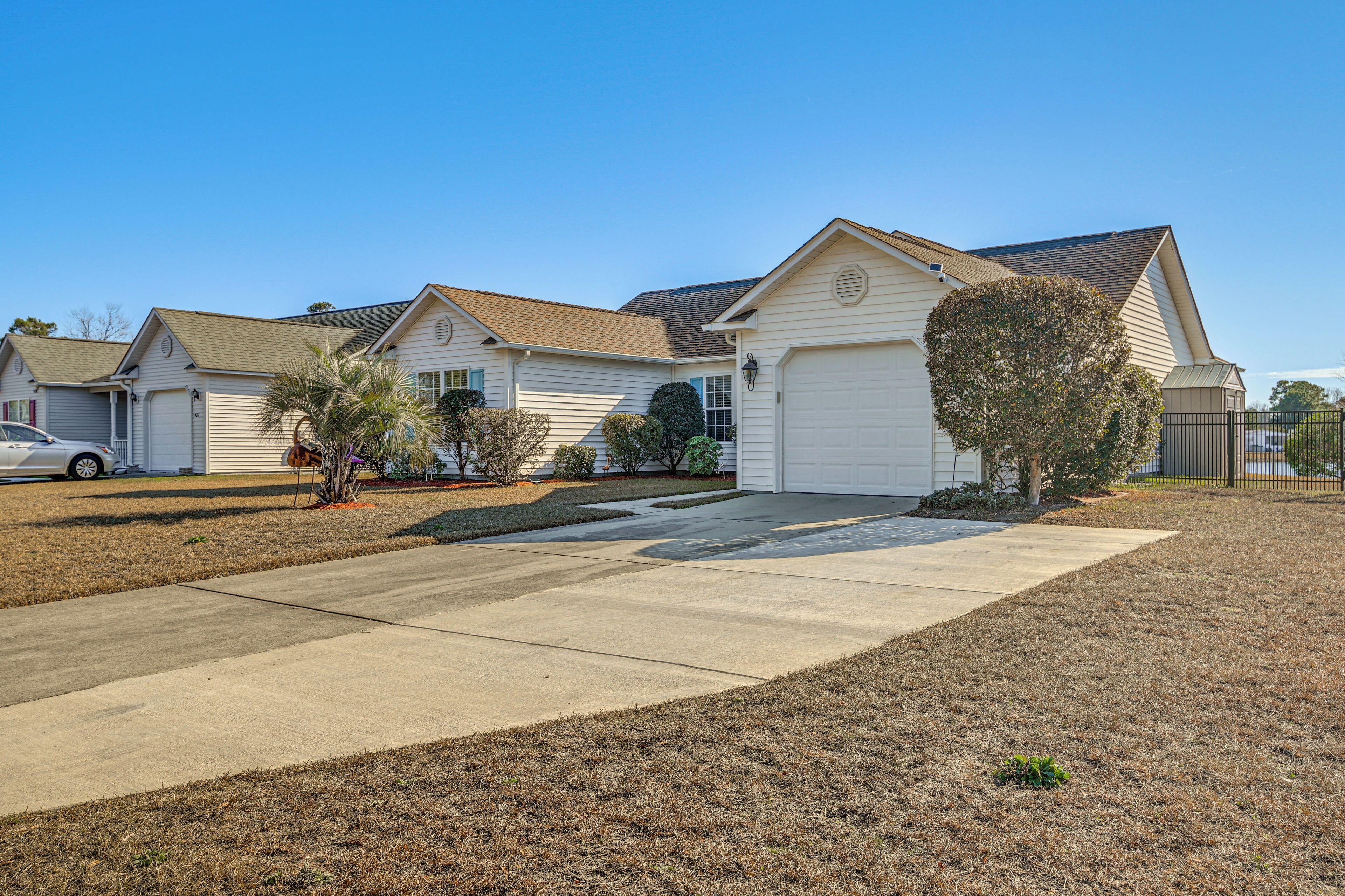 A row of single-story houses with attached garages, a clear driveway, and a well-maintained lawn.
