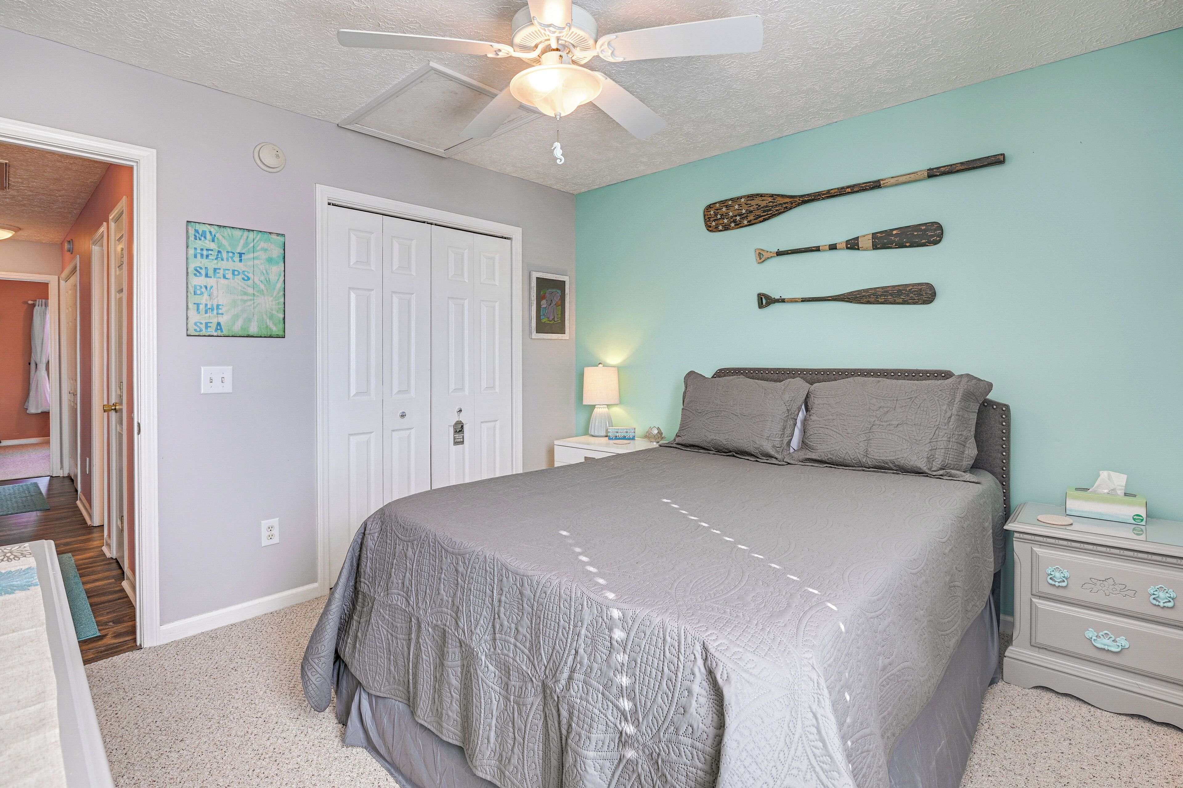 A bedroom with a bed, a nightstand, a ceiling fan, and wall-mounted paddles.