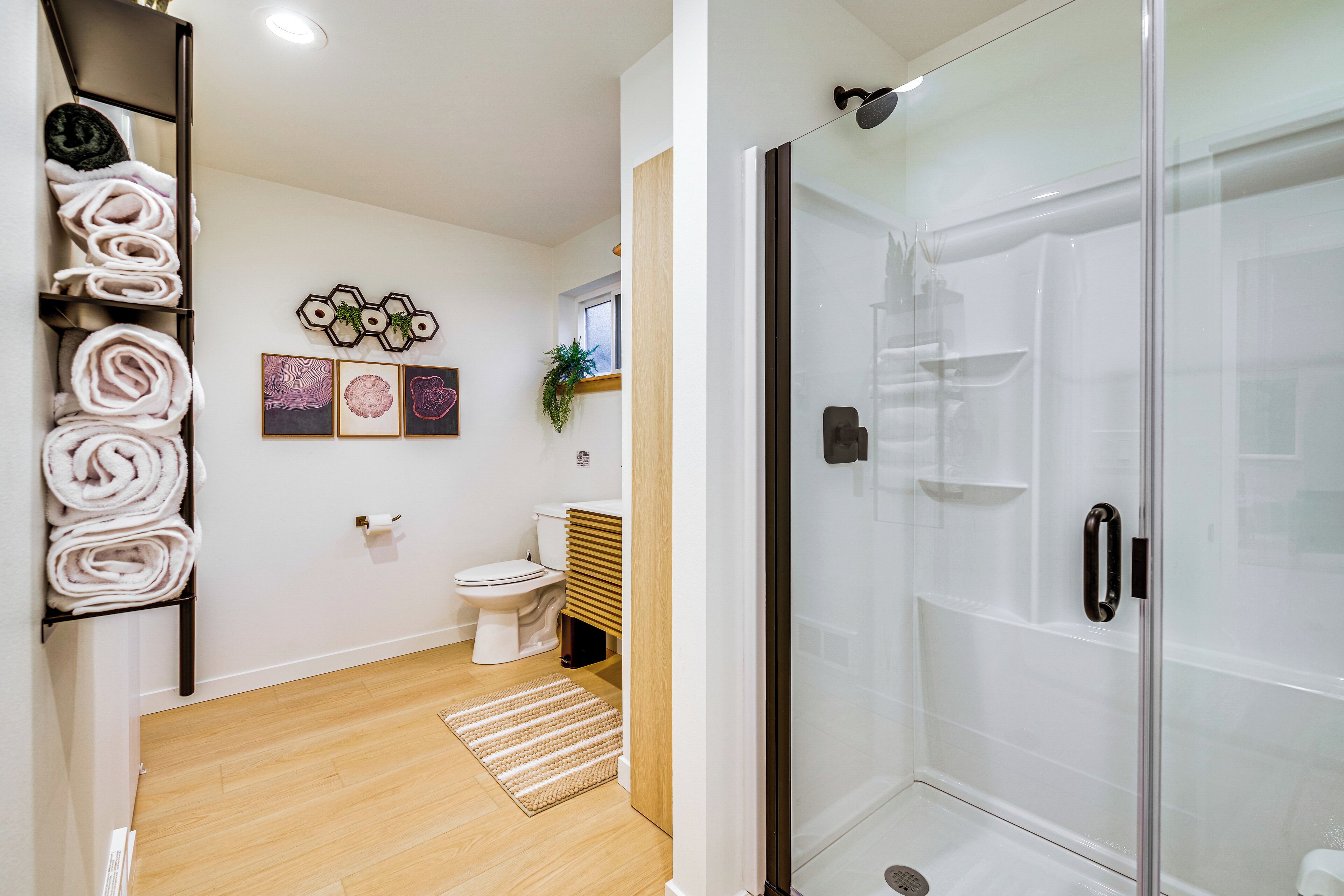Un baño con inodoro, ducha con puerta de vidrio y toallero con toallas dobladas.