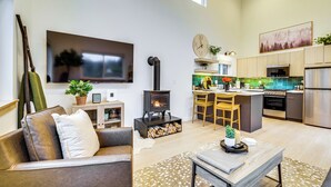 Ett modernt kök med en central köksö, en inbyggd spis och en stor platt-TV som är monterad på väggen.