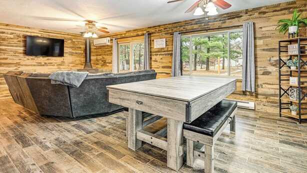 A cozy room with a wooden floor, a sofa, a table, and a ceiling fan. - Canal-front Cabin: Dock & Fire Pit in New Lisbon (New Lisbon)